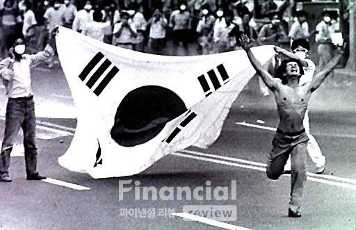 1987년 대통령 직선제를 요구하는 시민들이 태극기를 앞세우고 시위를 벌이고 있다.